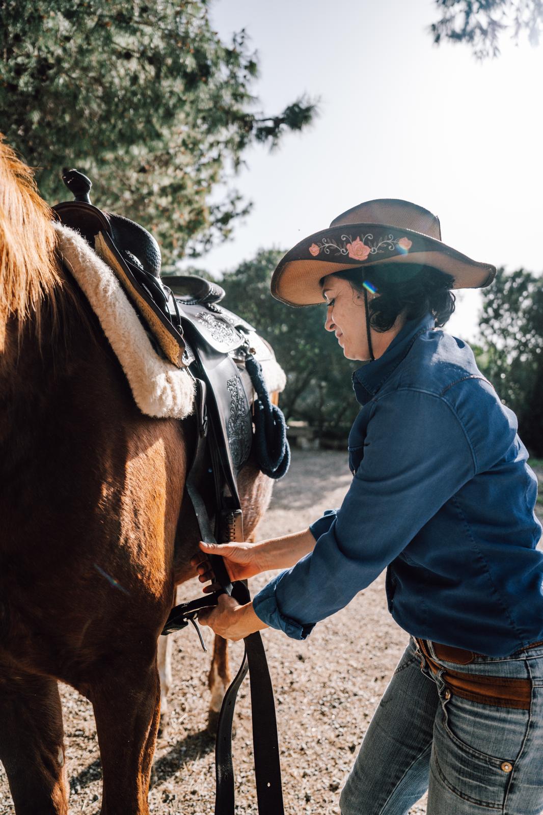 Si stringe il sottopancia della sella western prima della passeggiata a cavallo